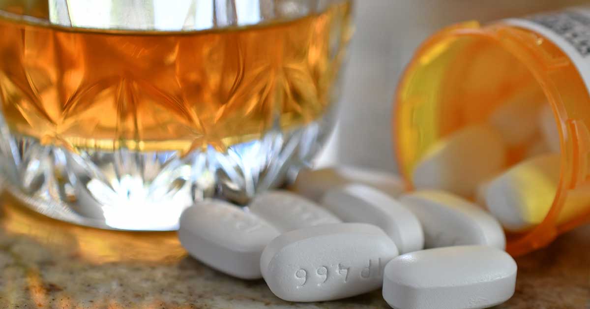 Pillendose neben einem alkoholischen Getränk, symbolisiert die Wechselwirkungen zwischen Citalopram und Alkohol