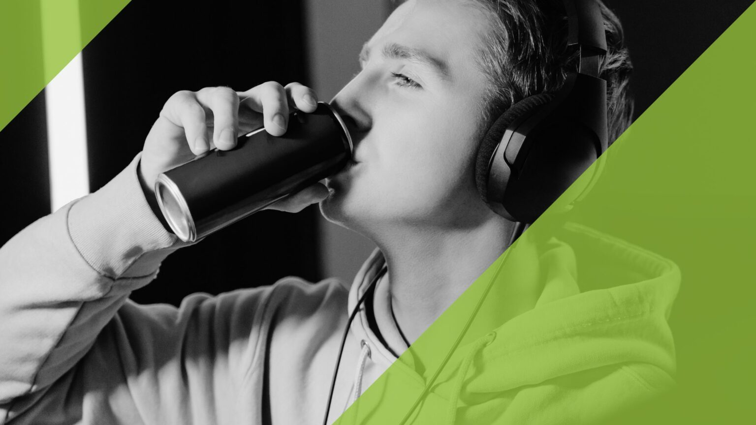 Junger Mann mit Kopfhörern, eine Dose Energy-Drinks trinkend