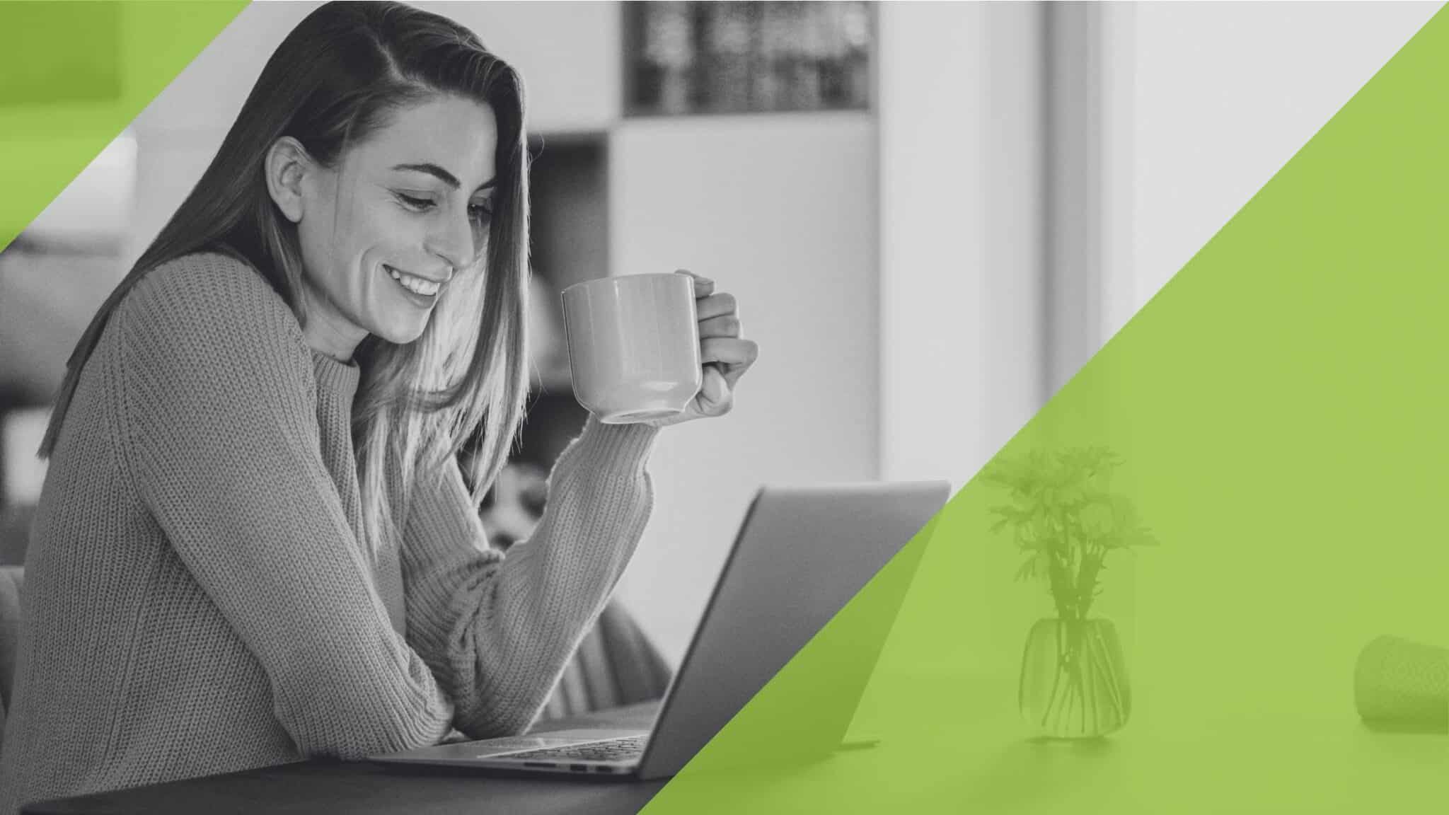 Eine Frau schaut entspannt auf einen Laptop-Bildschirm, mit einer Tasse in der Hand.