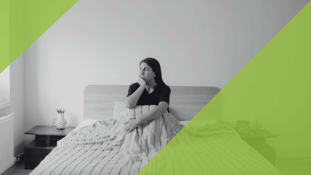 Nachdenkliche Frau sitzt in einem Bett und blickt aus dem Fenster, symbolisiert Depression.