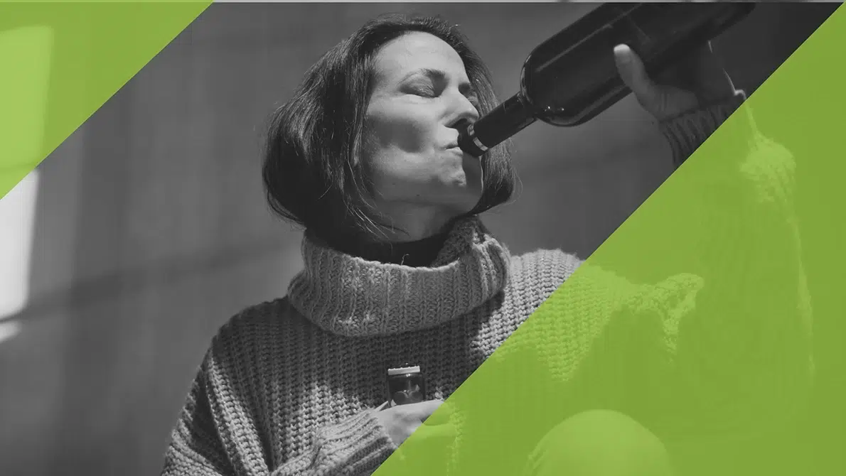 Frau trinkt Weinflasche, gefährliche Kombination von Alkohol und Amitriptylin dargestellt.